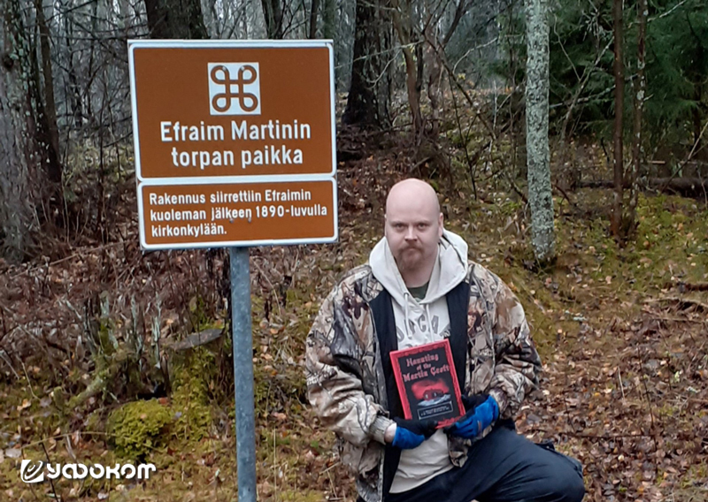 Юкка Стениус со своей новой англоязычной книгой о полтергейсте «The Haunting of Martins Croft» у знака, отмечающего первоначальное место расположения дома Эфраима Мартина, перенесенного в 1890 году. Фото из журнала «Ylojarven Uutiset», 2019 год.